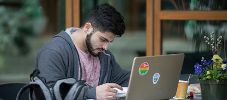 Student on computer sitting outside